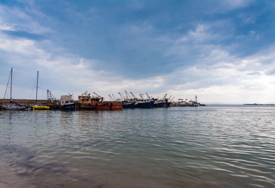 Recambios Marinos JJM, mantenimiento y reparación naval en Les Cases d'Alcanar. Hay un faro en el muelle marítimo con barcos.